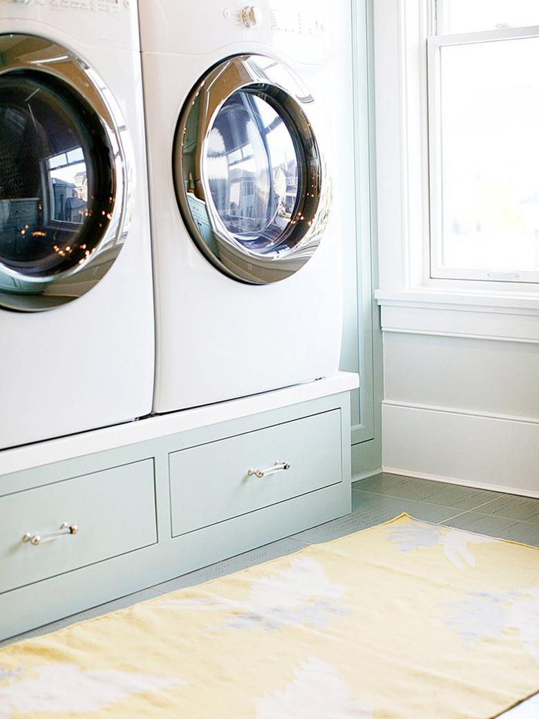 washer and dryer on pedestal with drawer storage in laundry room