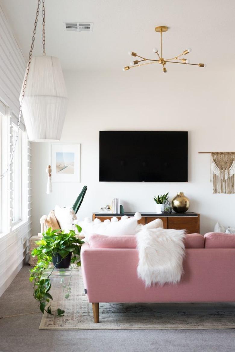 Modern living room with gold chandelier and hanging paper lantern.