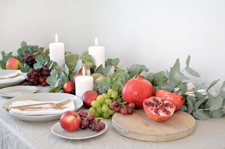 a table runner made of bunches of eucalyptus garnished with pomegranates and grapes