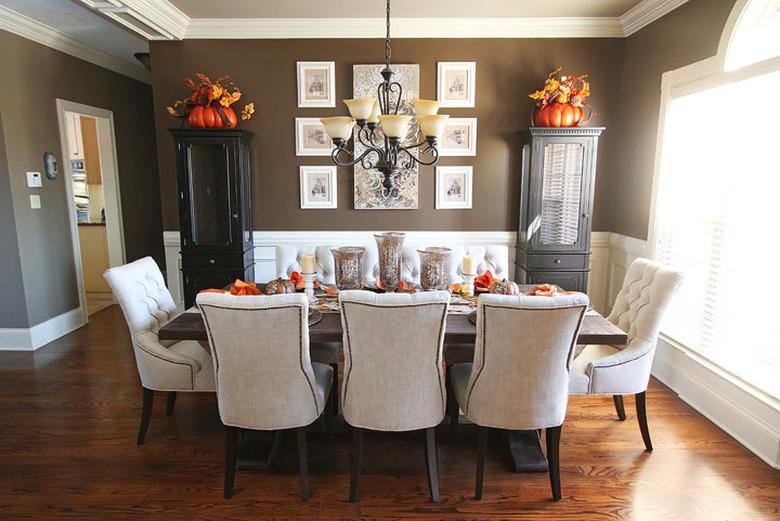 Brown walls and white wainscoting surrounding a dining table.