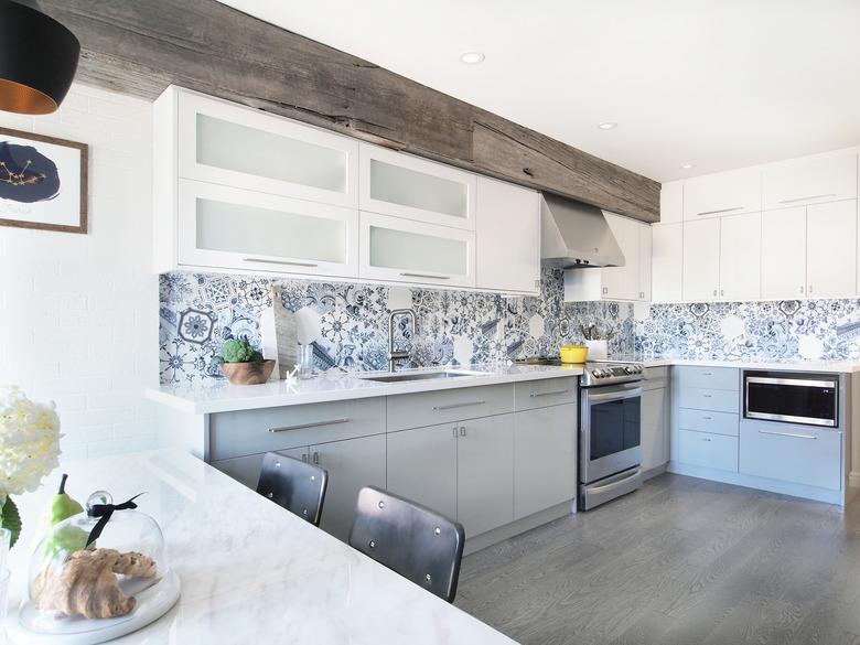 industrial L-shaped kitchen with white cabinets and patterned backsplash