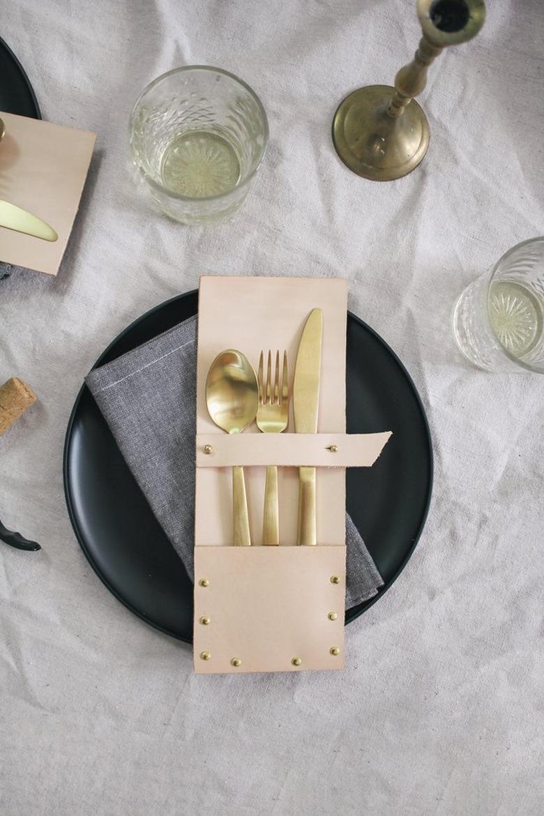 leather and brass studded flatware pack on a black plate with napkin