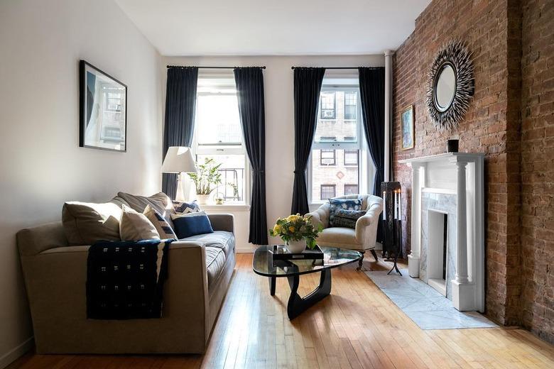 white arrow living room with fireplace, couch, brick wall, and coffee table