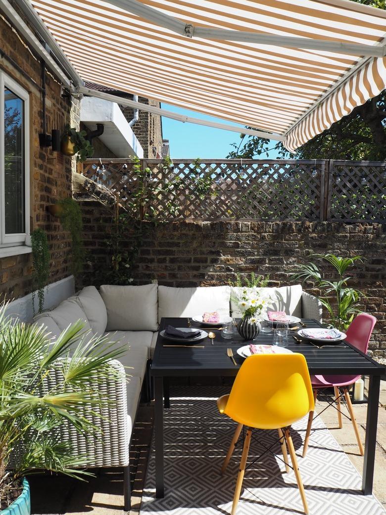 covered backyard patio with sectional sofa and colorful chairs