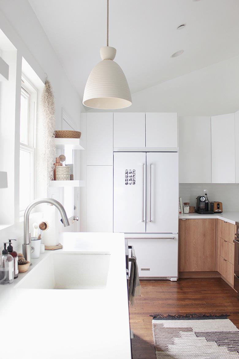 Modern kitchen lighting idea with pendant light over sink and two tone cabinets