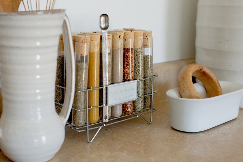 'Dean & DeLuca' spice vials and white dish ware on a neutral kitchen counter