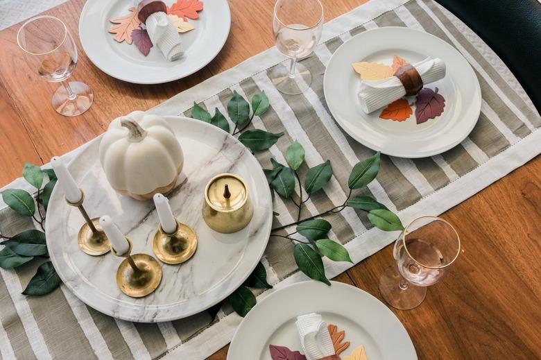 Minimalist striped table runner with dishware and foliage decor on wood table