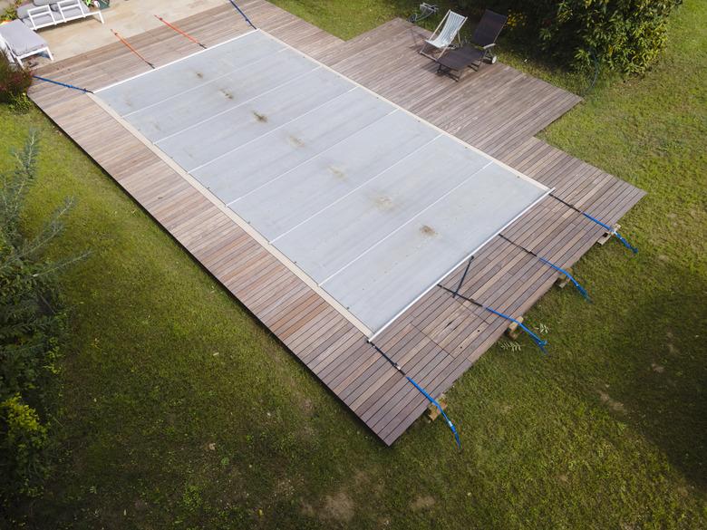 Drone photo of pool which is covered with grey pool tarpaulin, cover and prepared for winter