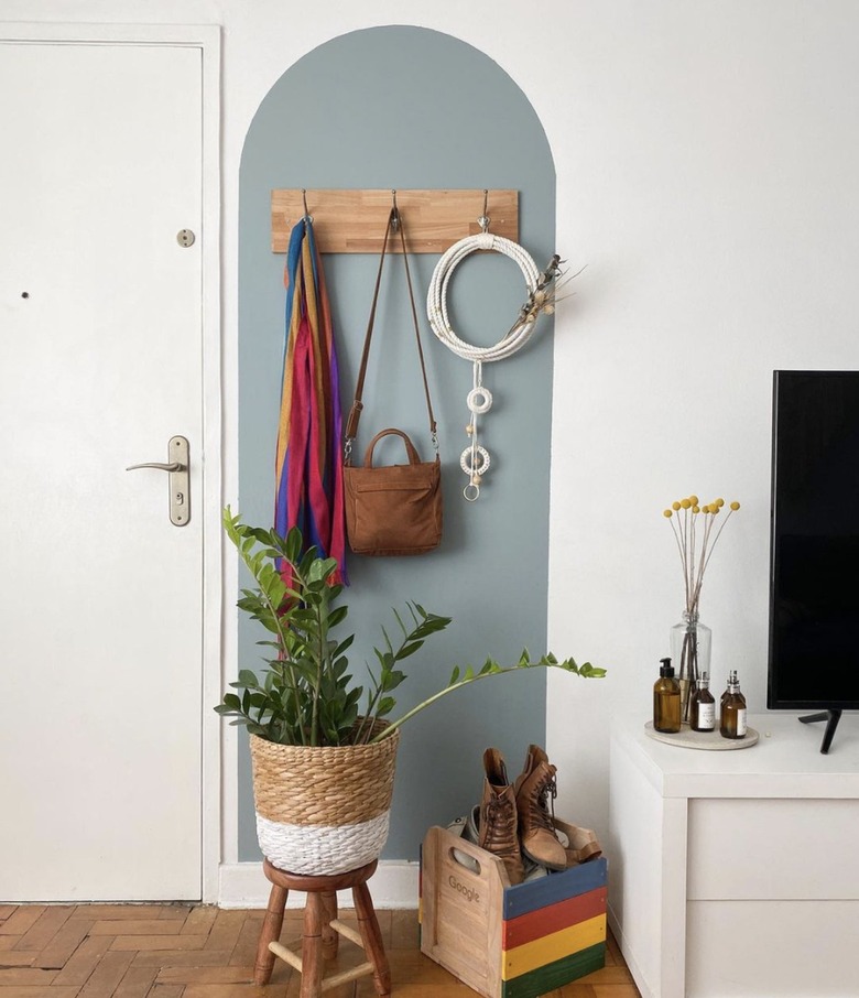 Entryway with sky blue arch accent, wood coat rack and a woven basket.