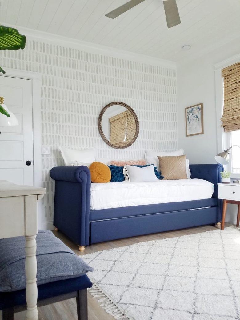 Living room with DIY patterned gray accent wall, blue sofa and bamboo blinds.