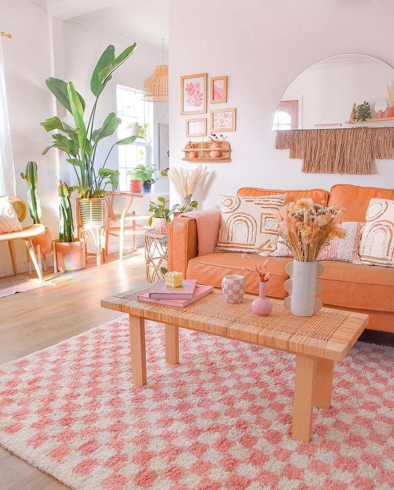 living room with orange couch and pink and white checkerboard rug