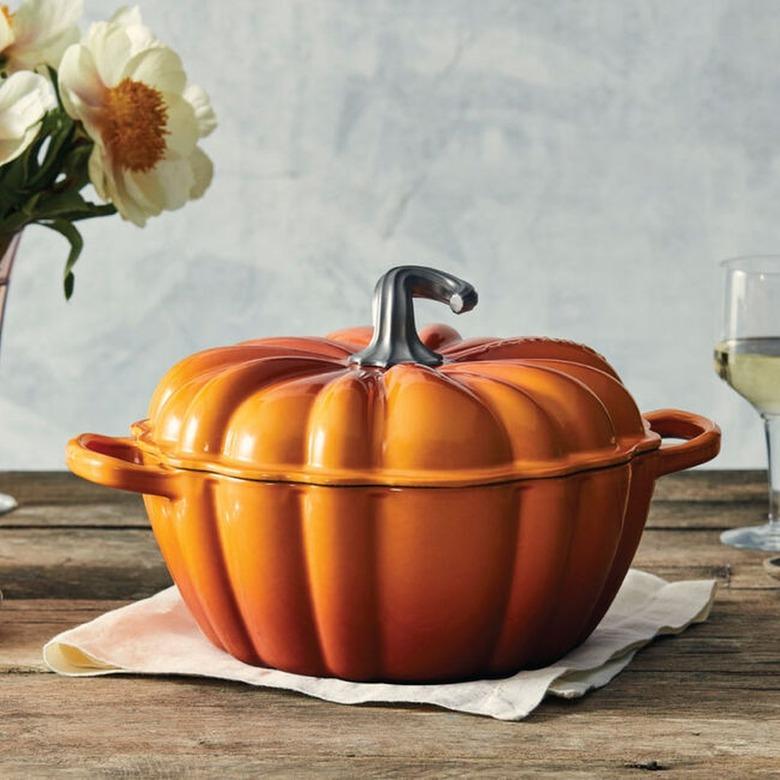 An orange dutch oven shaped like a pumpkin