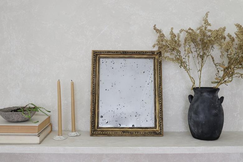 DIY antique gold mirror on shelf with dried flowers and beeswax candles