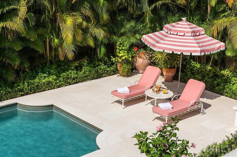 art deco decorating on a budget with lounge chairs and striped umbrella by pool