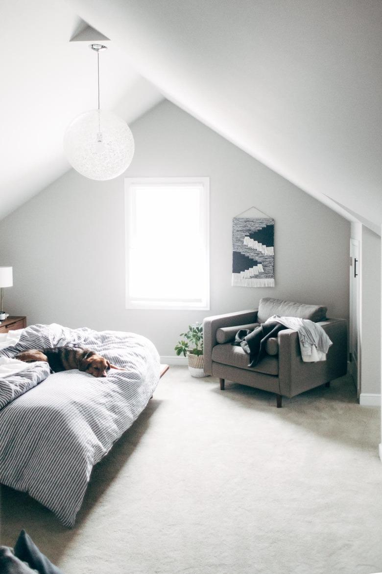 Attic bedroom idea with white, minimal decor and white circular pendant light