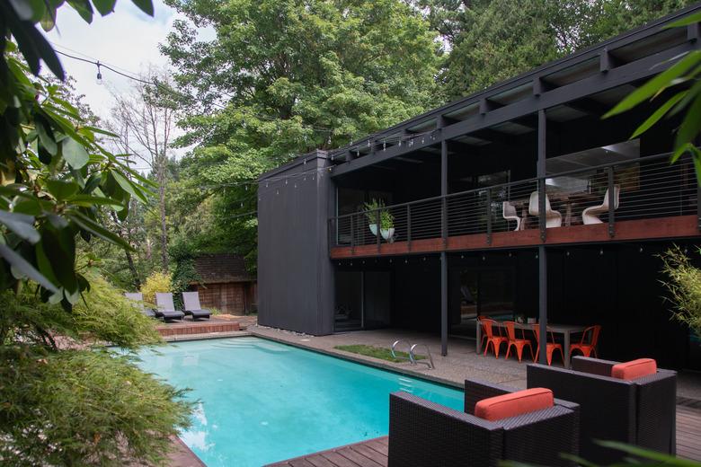 Midcentury backyard pool design  with black and red furnishings and exterior