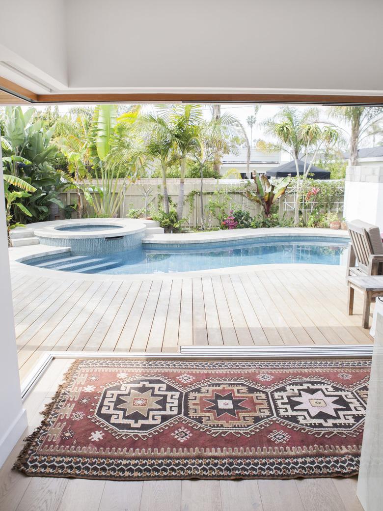 Curved backyard pool design with Turkish rug and palm trees