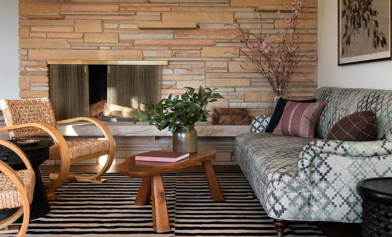 stone basement fireplace with wood bench and woven accent chairs