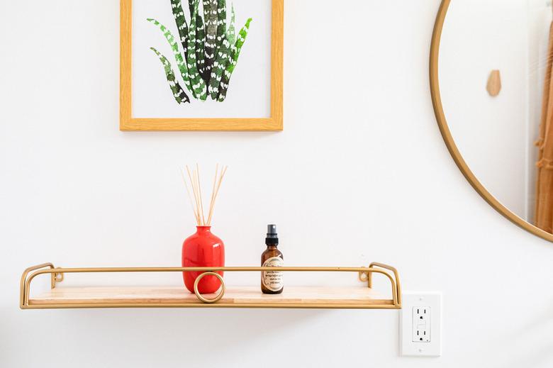 decorative wall shelf, circular mirror and picture of a plant