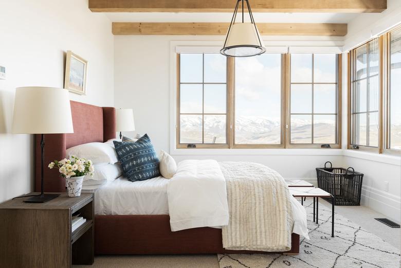 rustic bedroom chandelier hanging above bed with upholstered headboard