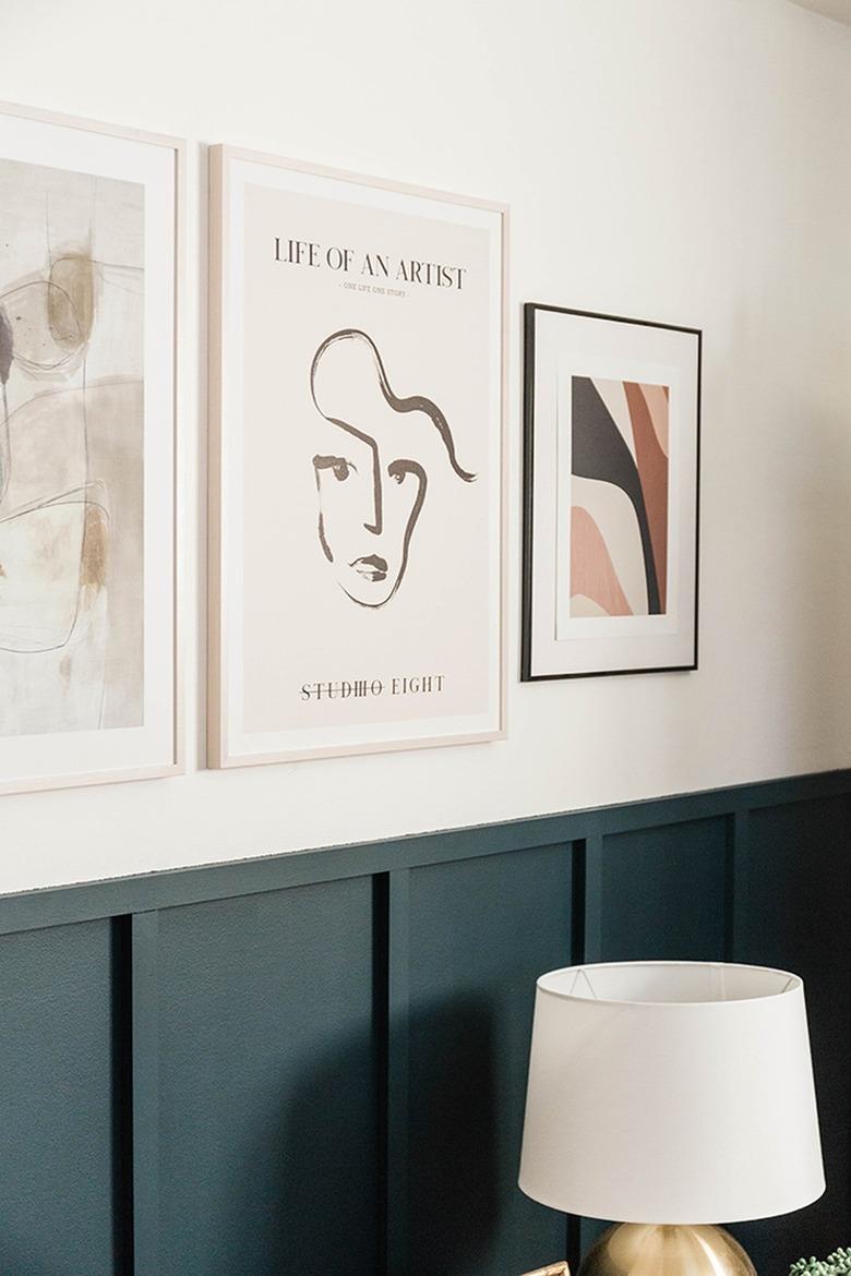 Living room with a blue board and batten wall with frame artworks, and a table lamp below