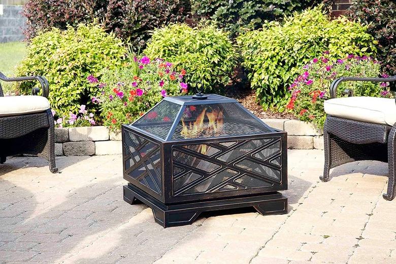 Fire pit in garden surrounded by bushes and patio furniture