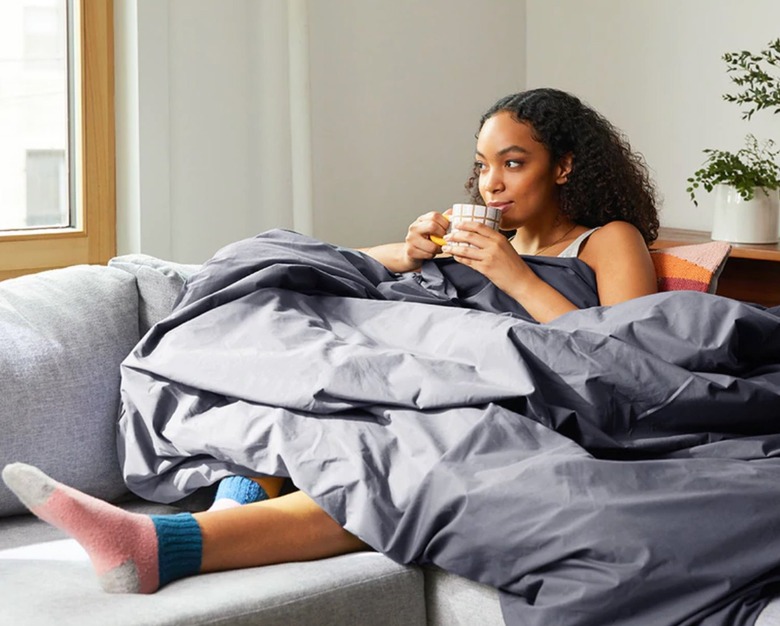 Girl on couch wrapped in weighted comforter.