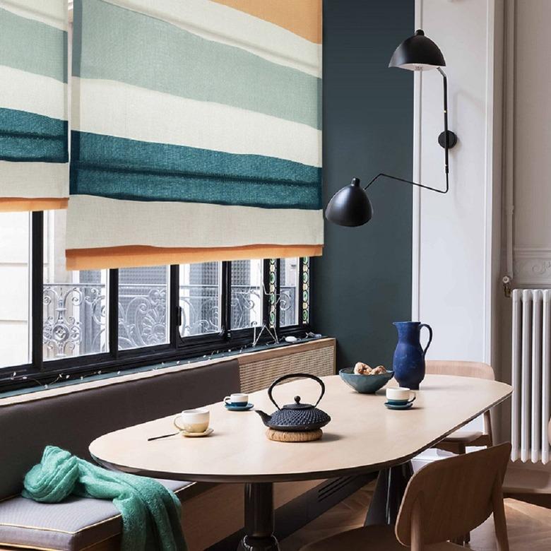 Colorful striped Roman shades over the dining room windows