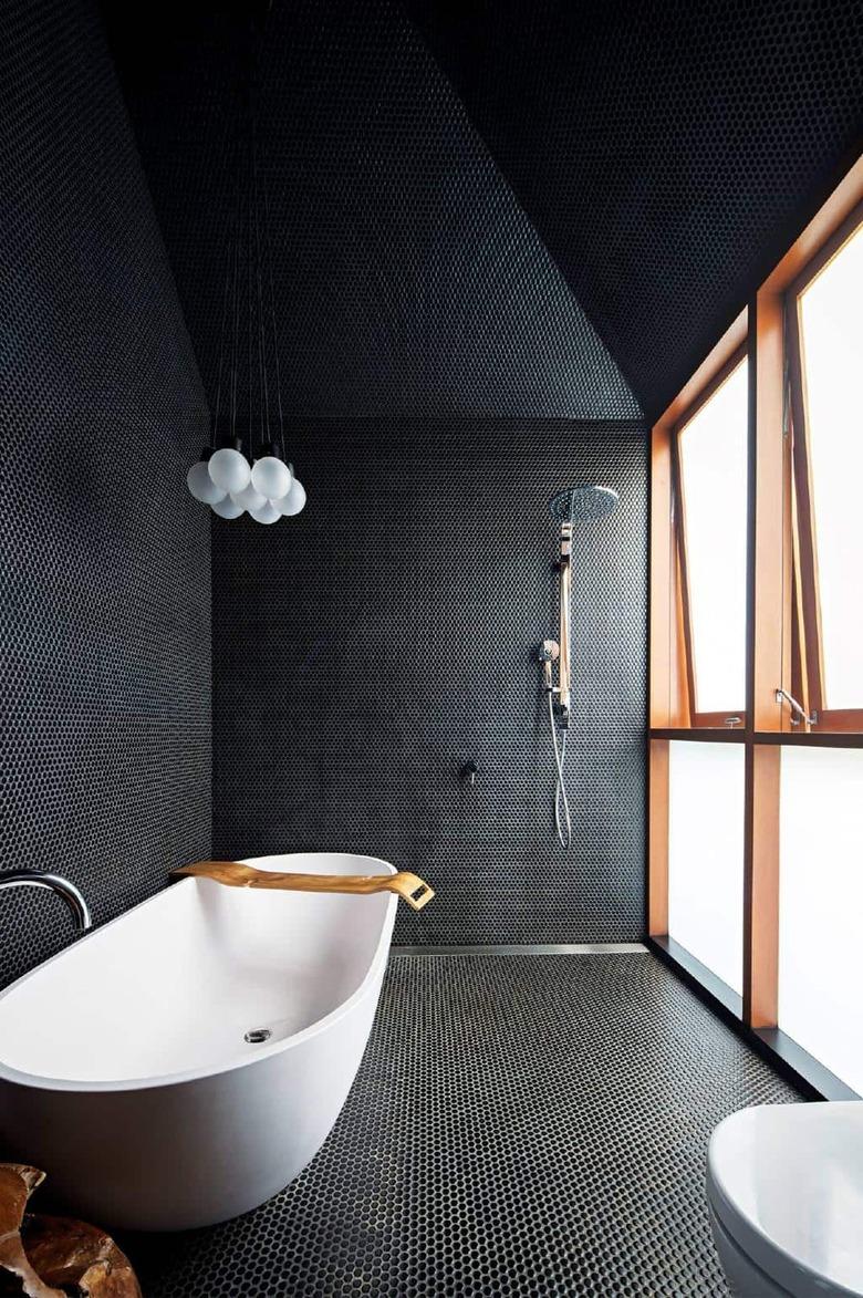 modern black bathroom with penny tile and freestanding tub