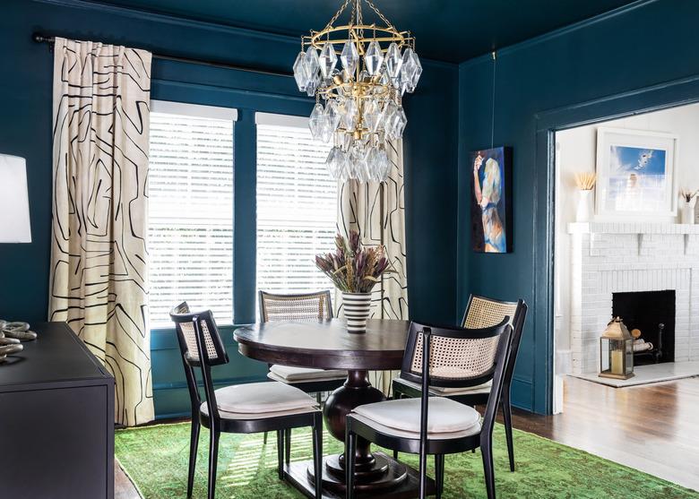 dark blue paint color in dining room with table and beige window treatments