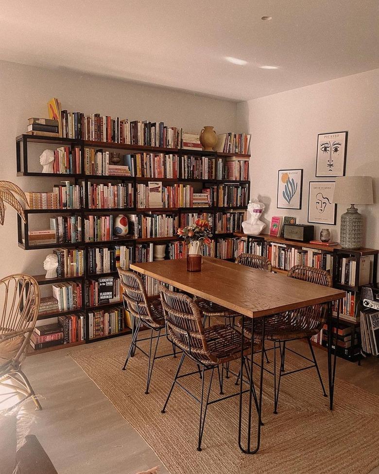 A black bookshelf kitchen with a wooden table and chairs.