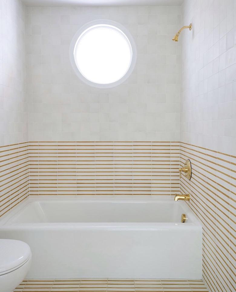 mustard striped tile with brass shower and tub fixtures