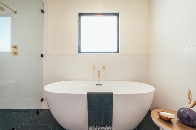 black and white bathroom with brass shower and tub fixtures