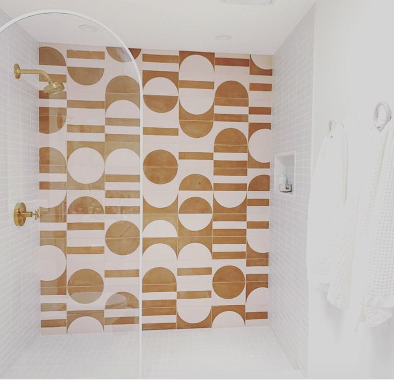 yellow and pink graphic wall tile with brass shower fixtures