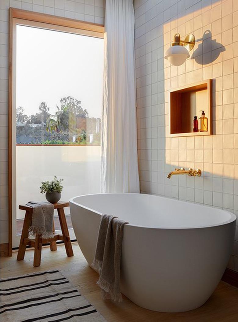 white bathroom with wood accents and brass tub fixtures