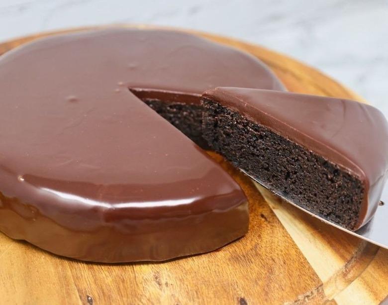 A slide of Oreo cake being cut on a wooden cake board.