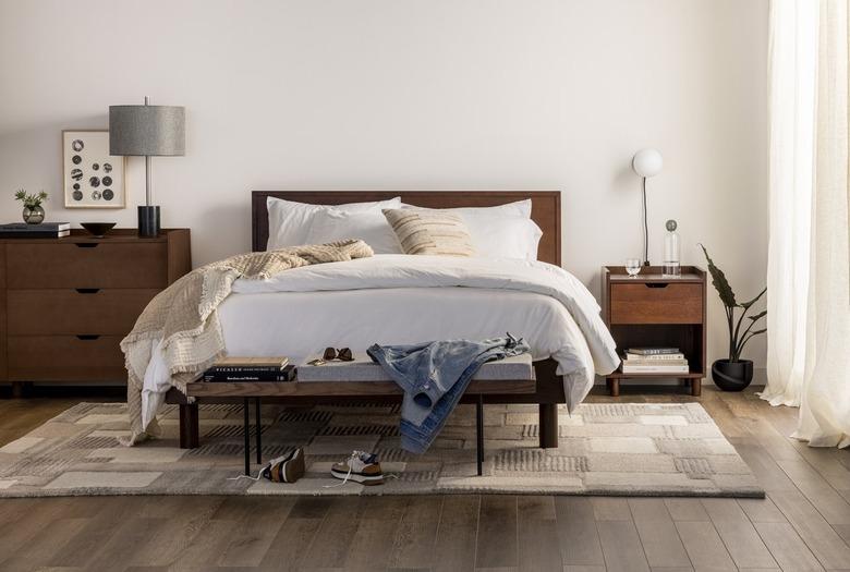 Burrow's Chorus Bed frame and headboard supporting a mattress covered in white linens and pillows.