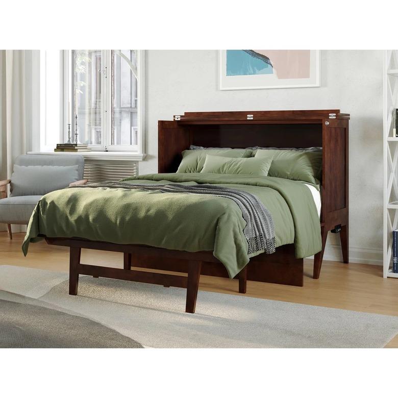 An open cabinet bed featuring a dark wood headboard and medium green bedding.