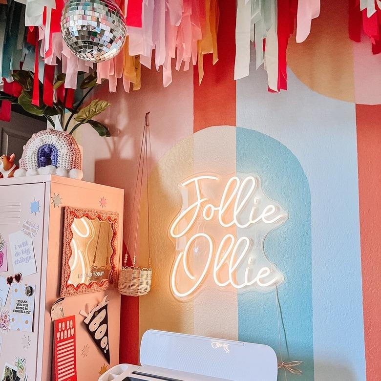 room with striped pastel walls, disco ball, and neon art