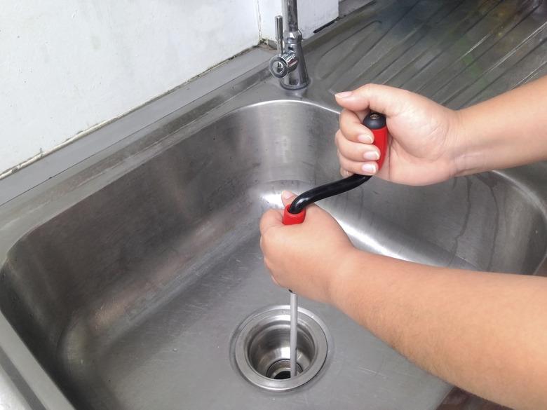 Woman's hand are breaking through the pipes. Clog pipe cleaner by yourself. Flexible spring drain cleaner.