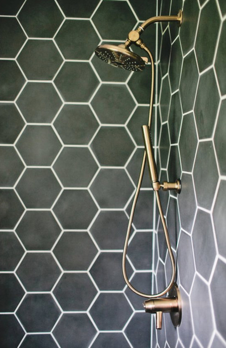 Moss green hexagon shower tiles with brass fixtures.