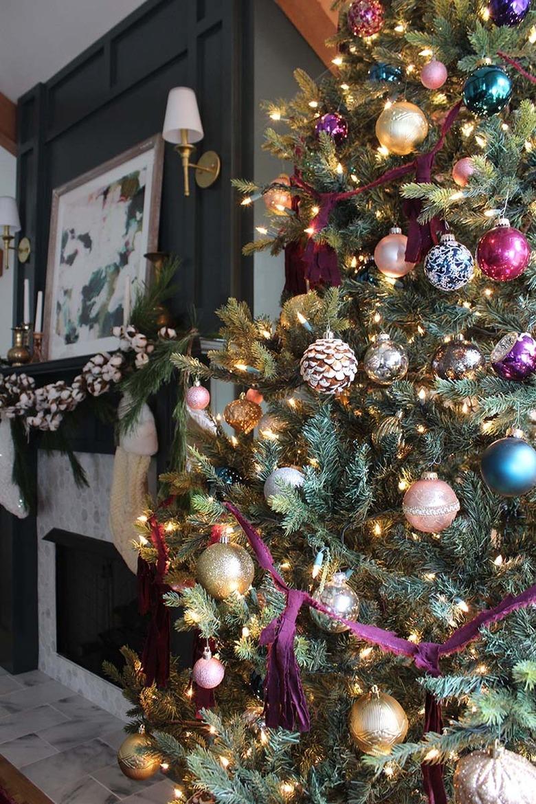 Dark living room with a Christmas tree with purple, gray, and gold ornaments.