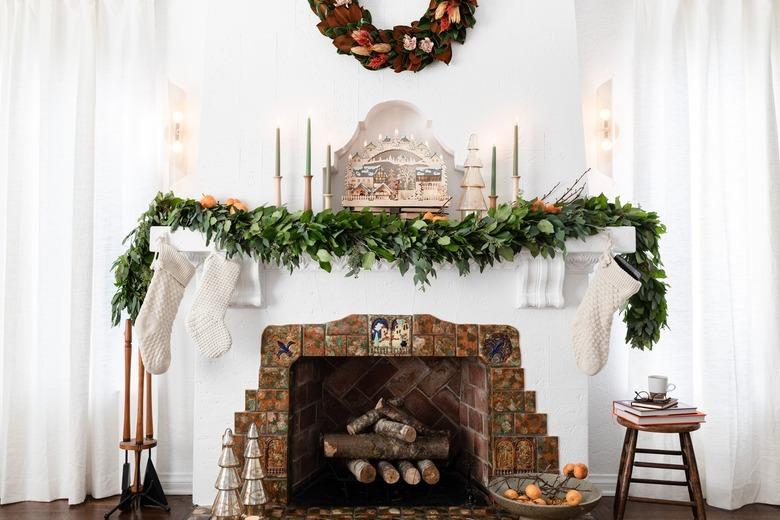 Mantel with garland and red wreath hanging overhead.