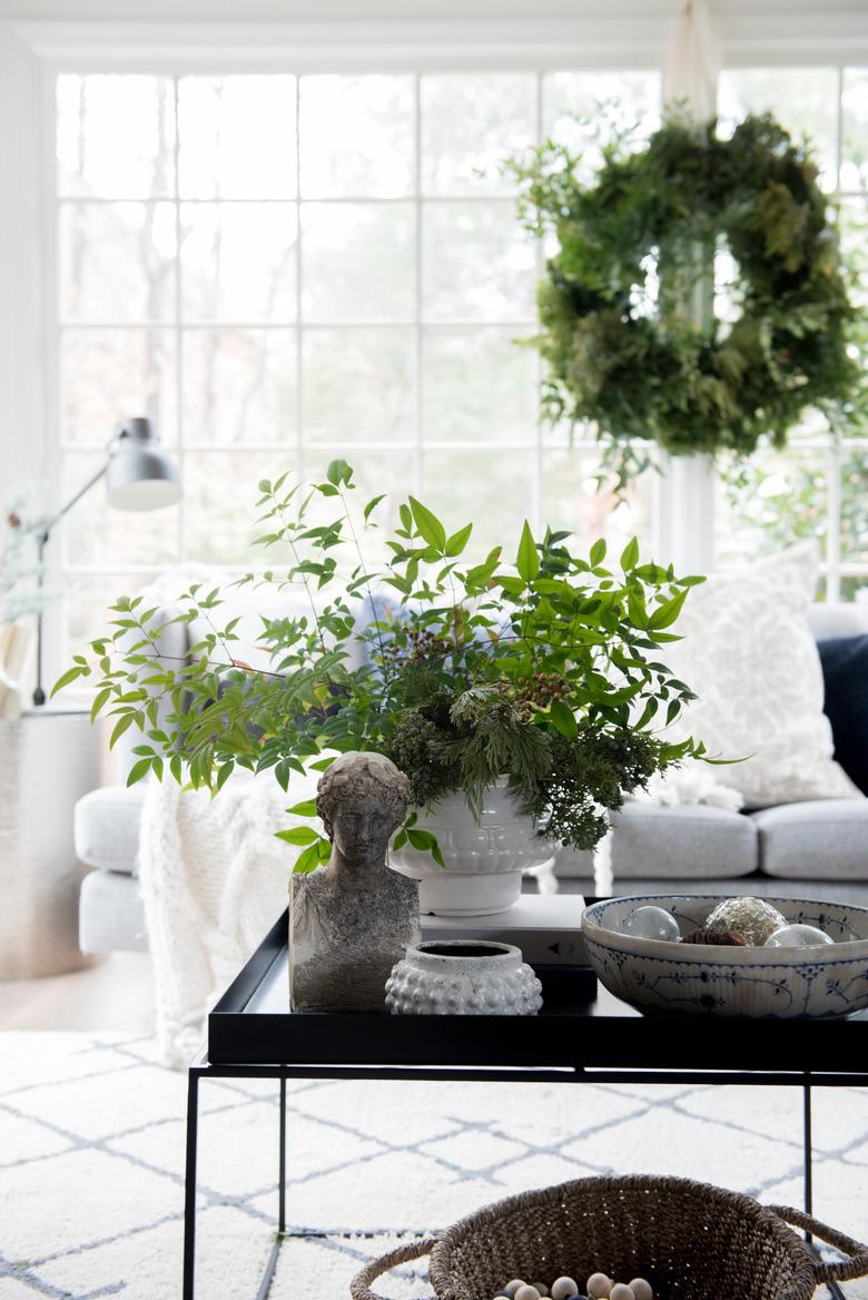 White sunroom with winter greens in vase and wreath hanging on windows