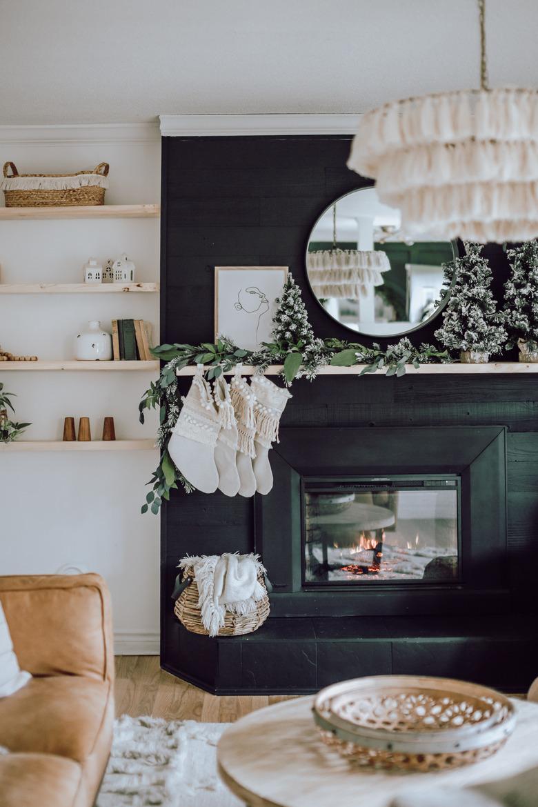 Black fireplace with macrame stockings, boho decor, and tasseled chandelier