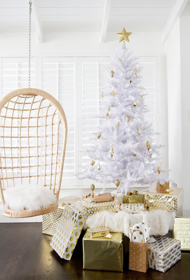 Christmas Tree Themes with White artificial Christmas tree, hanging can chair, wrapped presents.