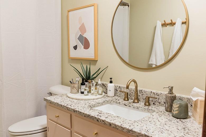 Beige painted wood vanity cabinet with a granite or quartz counter, in a neutral bathroom