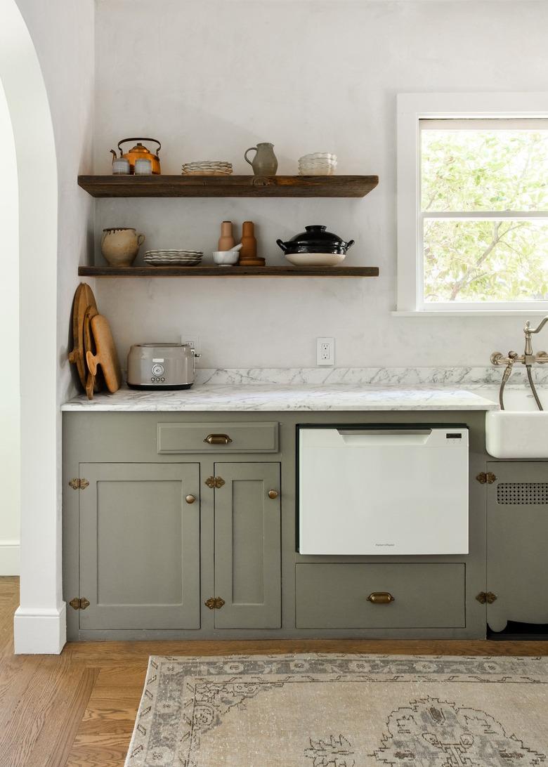 Minimalist kitchen with wood shelves gray cabinets, and a white marble or granite countertop.