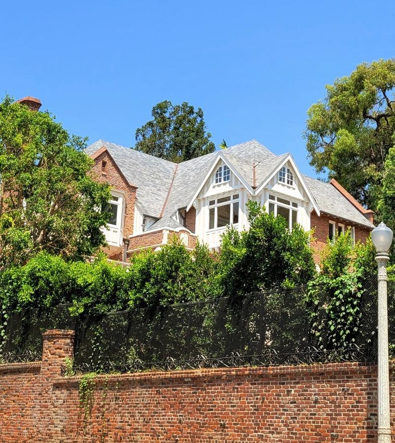 Brick home with gray shingle roof with brick fence