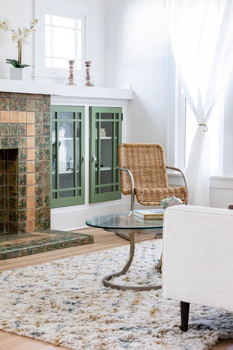 Contemporary living room with a tiled fireplace, wood floors and green cabinets